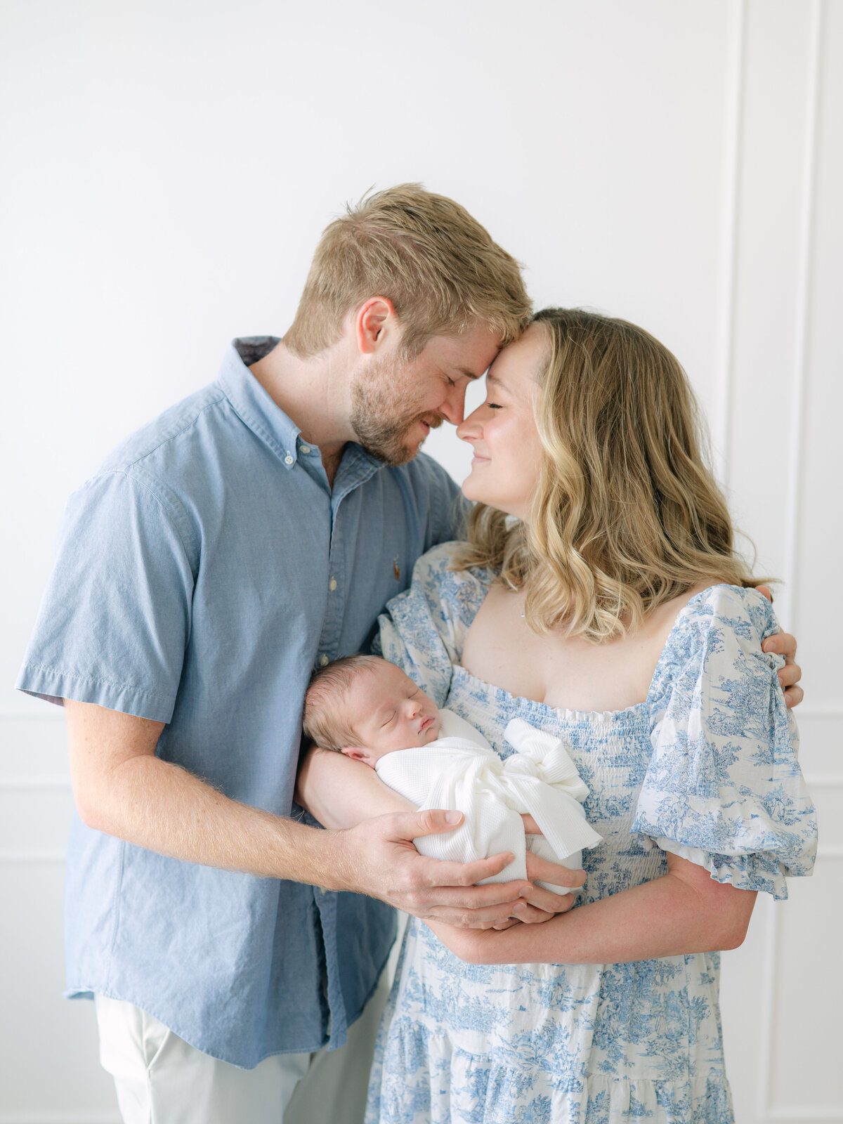 Mom and dad smiling with baby by apex newborn photography 