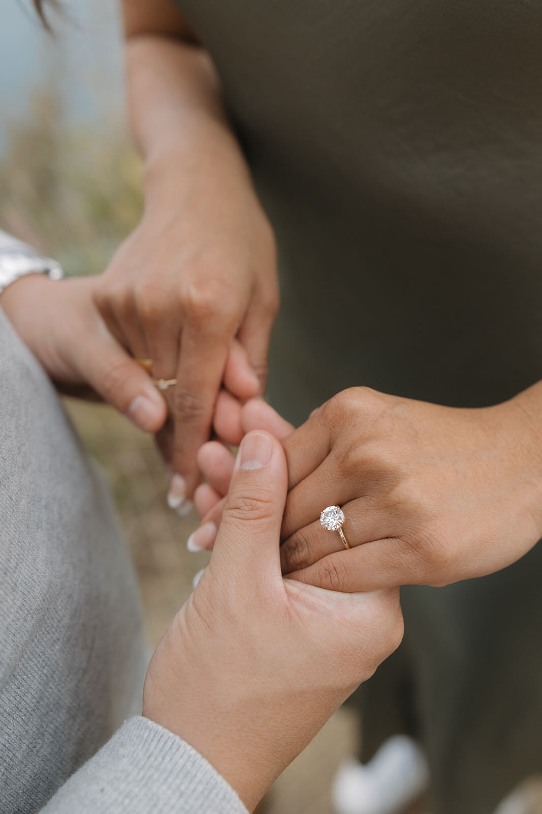Close up of an engagement ring as the couple holds hands