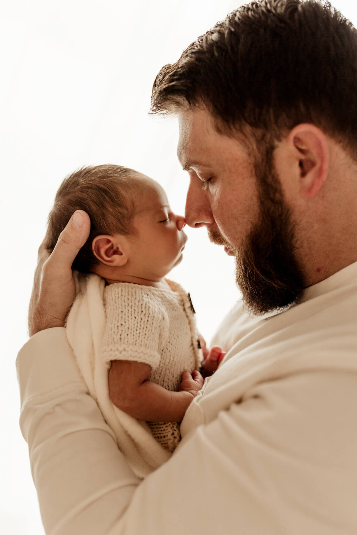 Father touches noses with his newborn son.