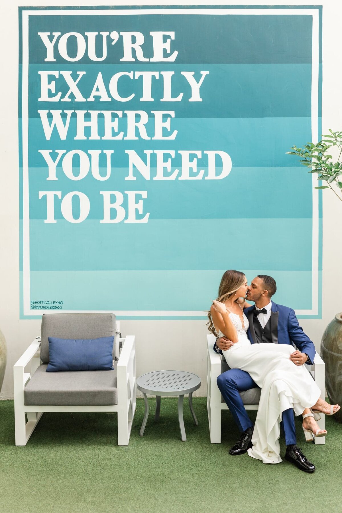 Bride and Groom kissing under sign that reads You're exactly where you need to be