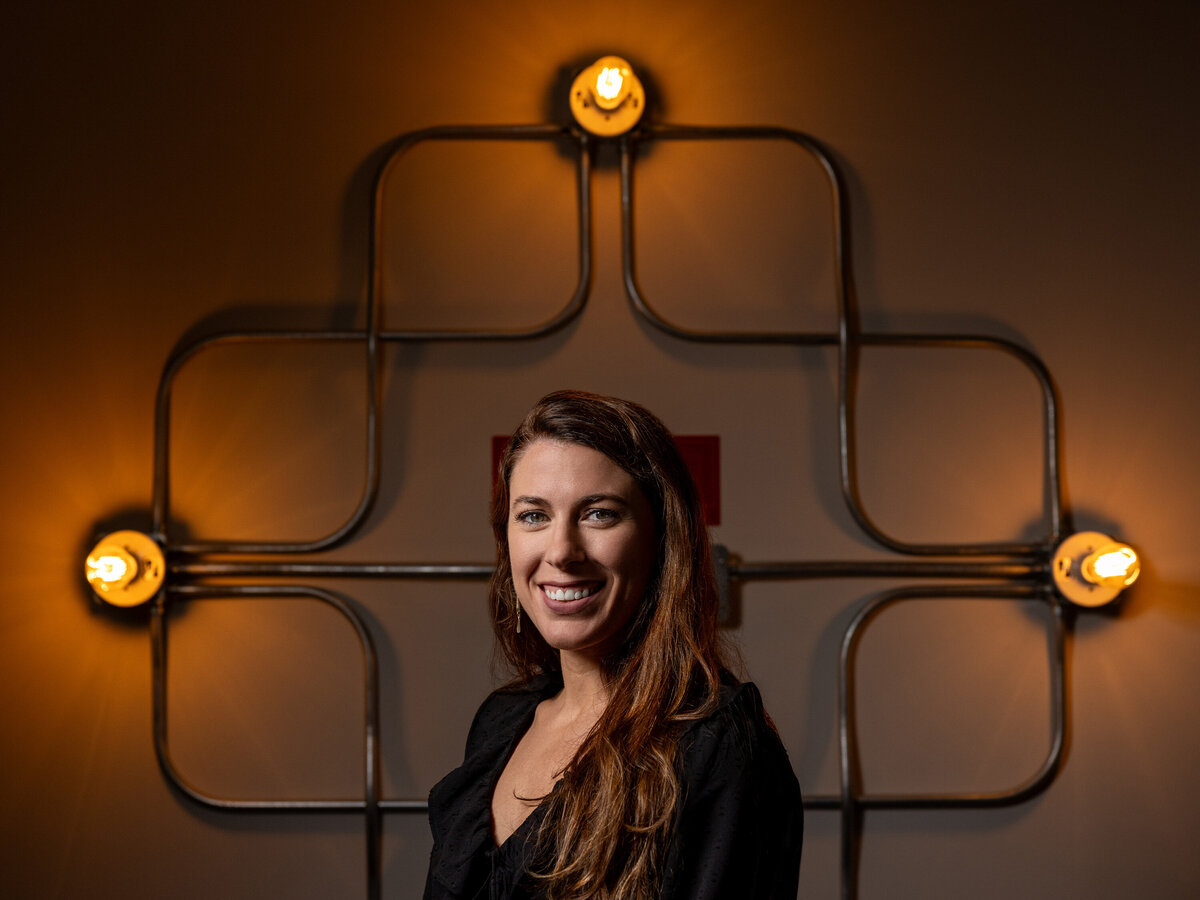 A woman smiling in front of an industrial style light