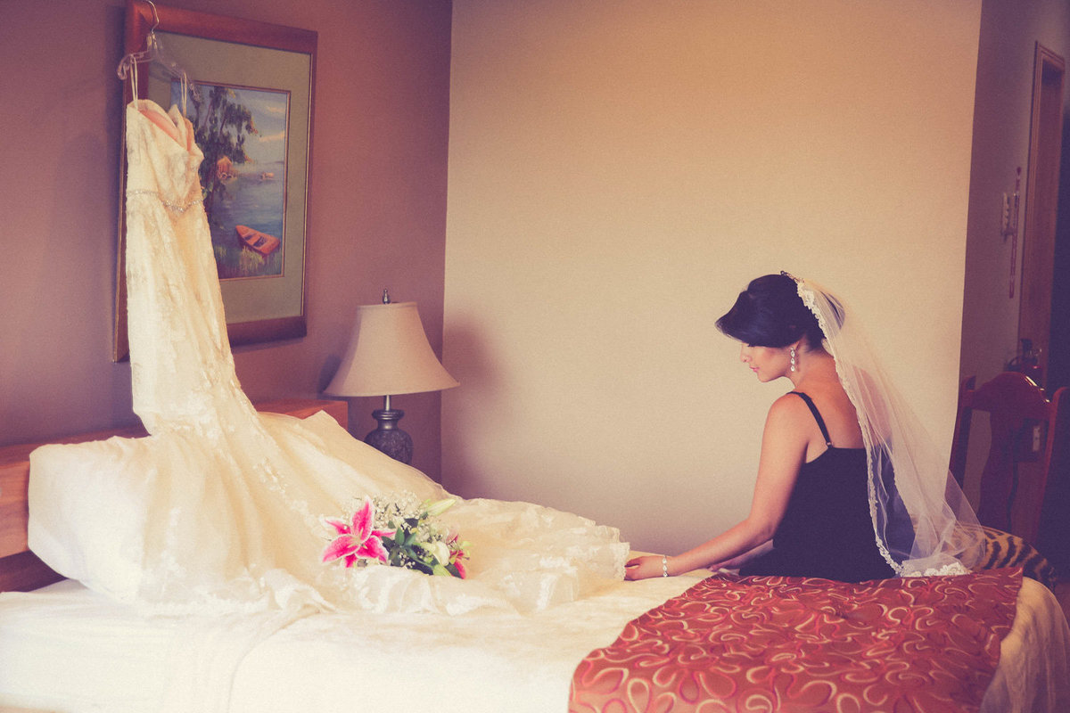 Bride looks at her wedding dress before getting dressed for the wedding. Photo by Ross Photography, Trinidad, W.I..