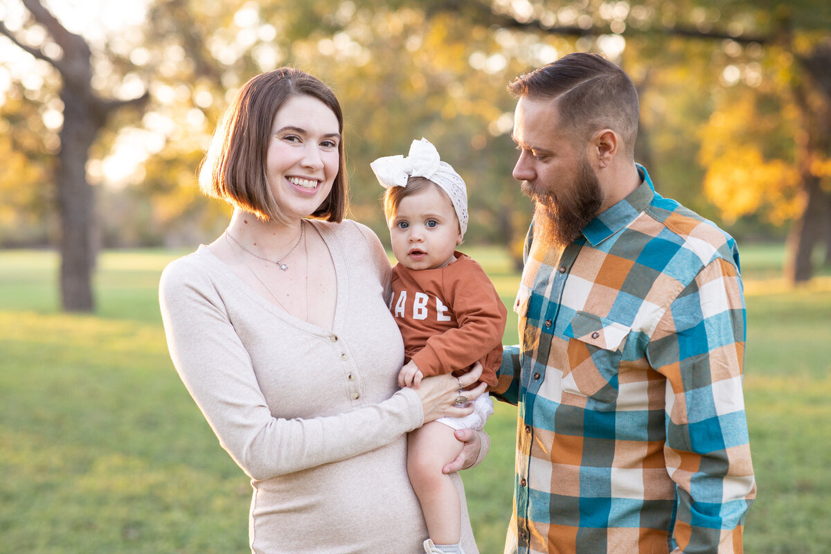 An Austin wedding photographer capturing a loving couple with their adorable baby in a park.