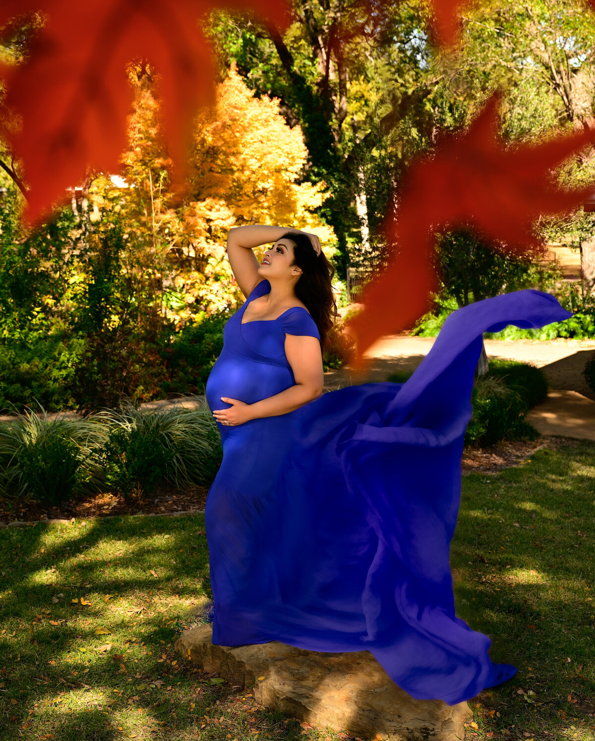 Autumn leaves fall in front of the camera during the maternity session at the botanical gardens