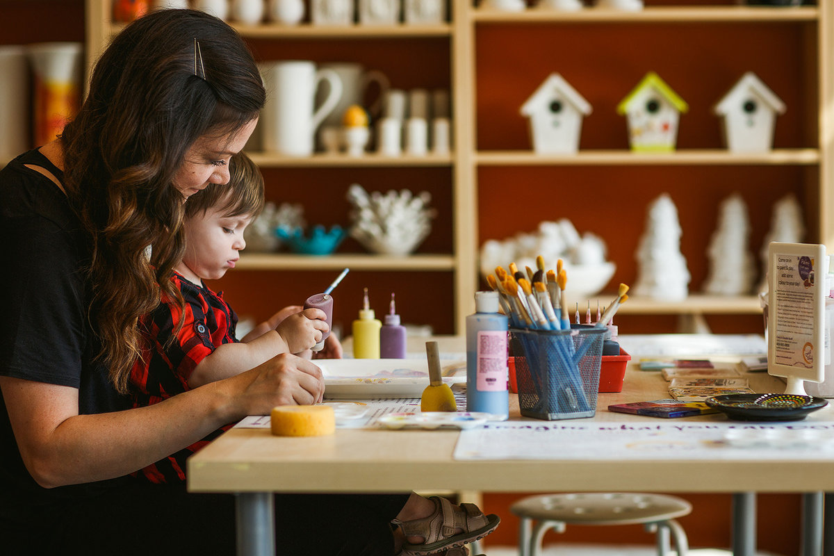 Commercial portrait of Mom and young child painting pottery