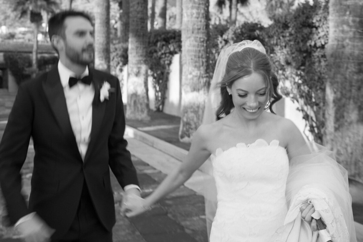 Bride and groom walking hand in hand through the palm courtyard at Royal Palms Resort in Phoenix, captured by luxury wedding photographers.