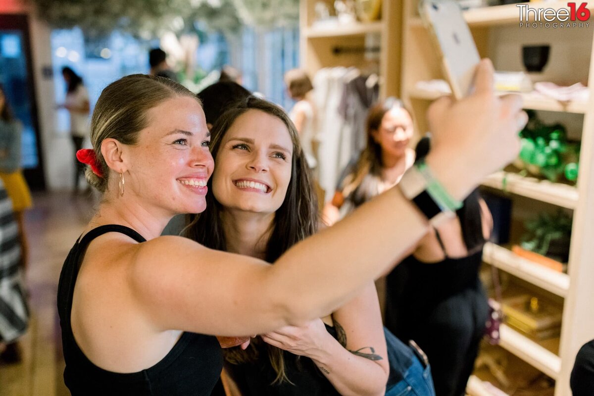 Two ladies pose together for selfie during a grand opening of a shop