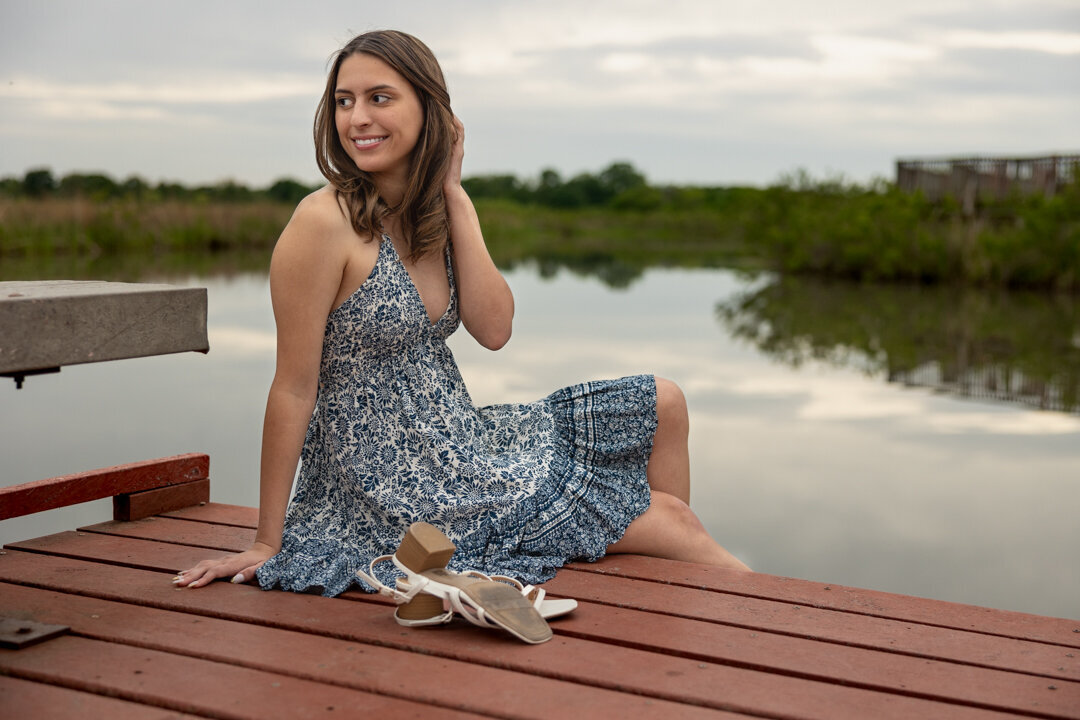 A senior girl sitting on a dock by a lake in Lawrence, KS