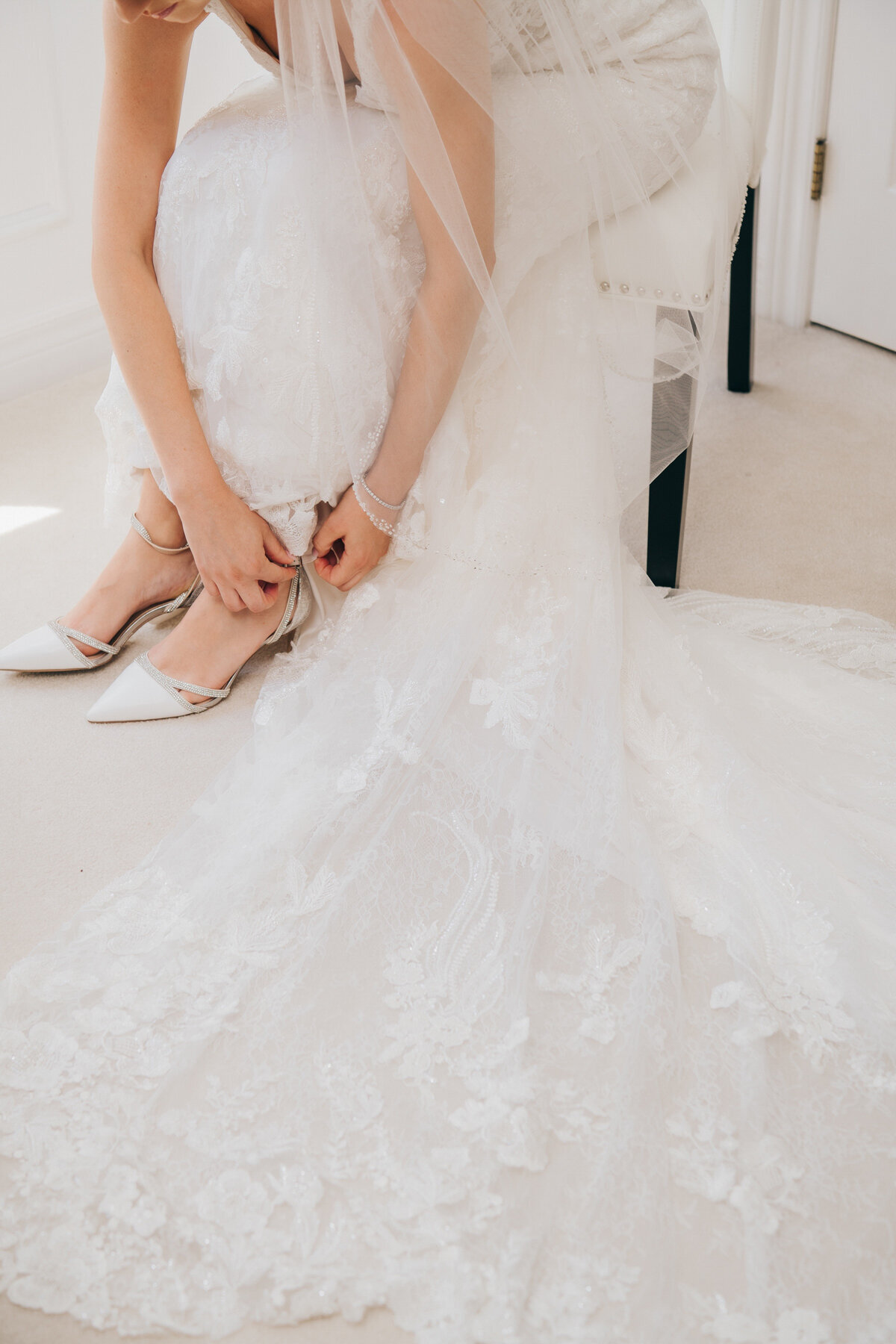 Th bride doing up her white wedding shoes