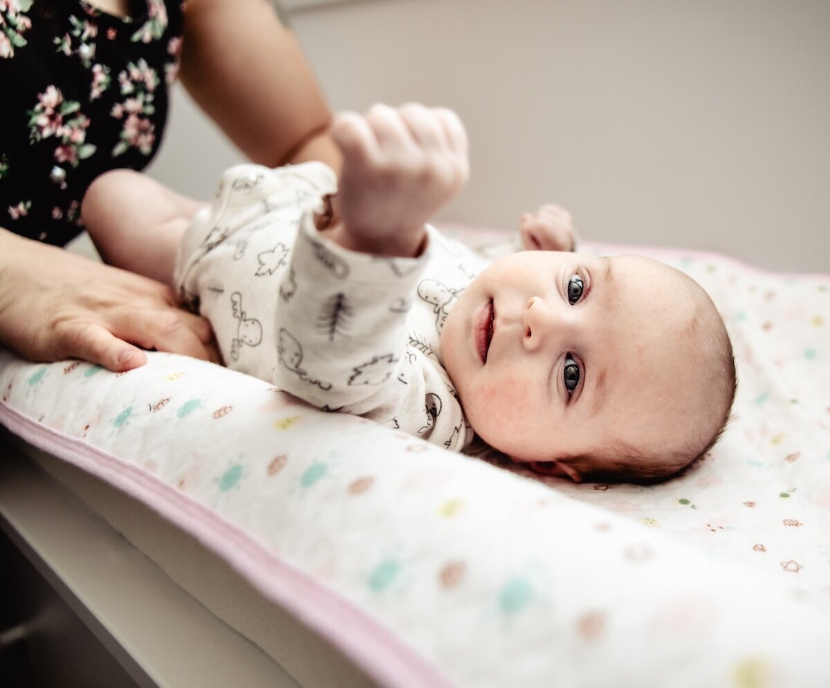 a new mom gets her two day old baby girl dressed on a changing table in her Edmonton nursery