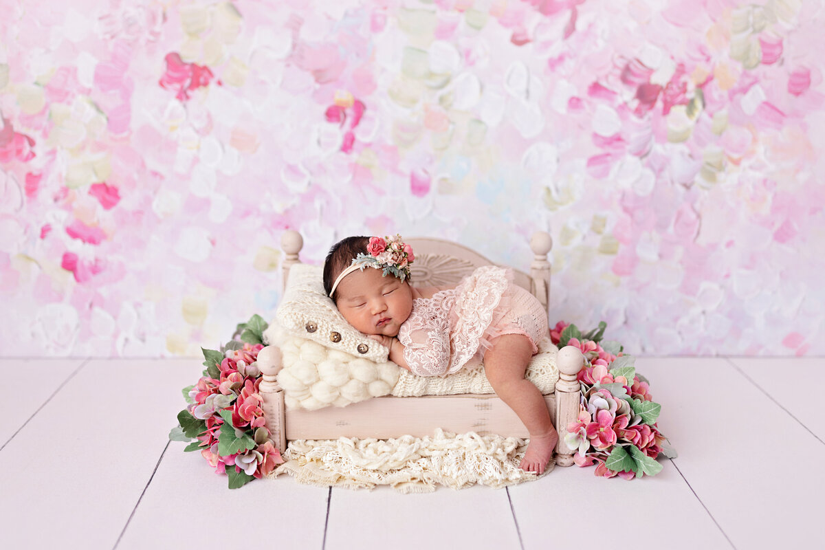 Newborn girl in pink tones surrounded by soft cherry blossom florals