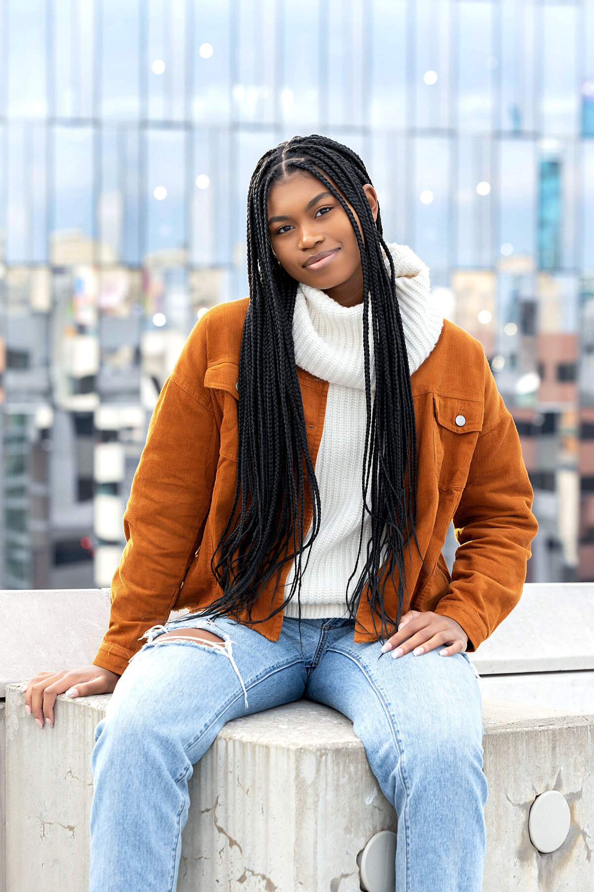 Detroit Z Lot Garage Senior Photoshoot | Detroit Michigan Senior Photographer, Senior girl wearing dark tan corduroy jacket, white cowl neck sweater, and stonewash destructed jeans on rooftop of a parking garage