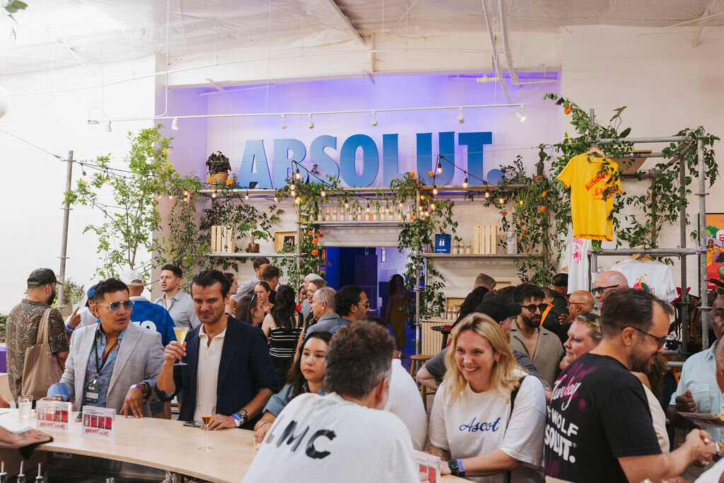 Guests gather around an Absolut-branded bar installation with greenery and ambient lighting, part of the immersive Absolut Studio activation produced.