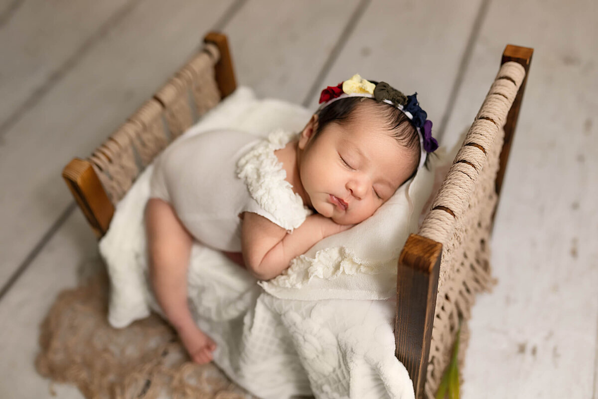 Two week old baby girl posed on photography studio bed.