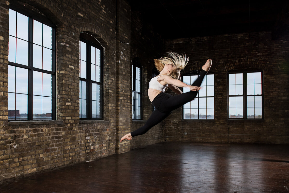 grad photo of girl in dance leap in studio