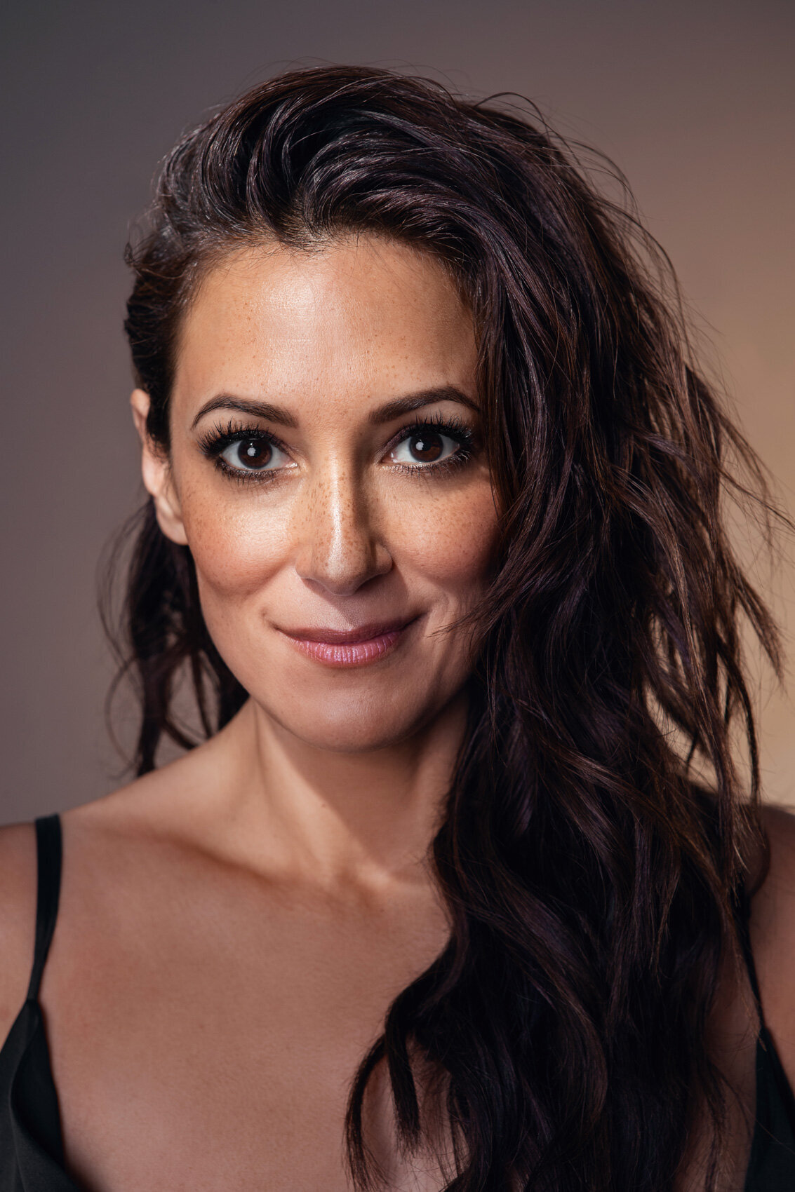 Bright portrait of Angelique Cabral with a warm smile and glowing complexion, photographed by Ylva Erevall.