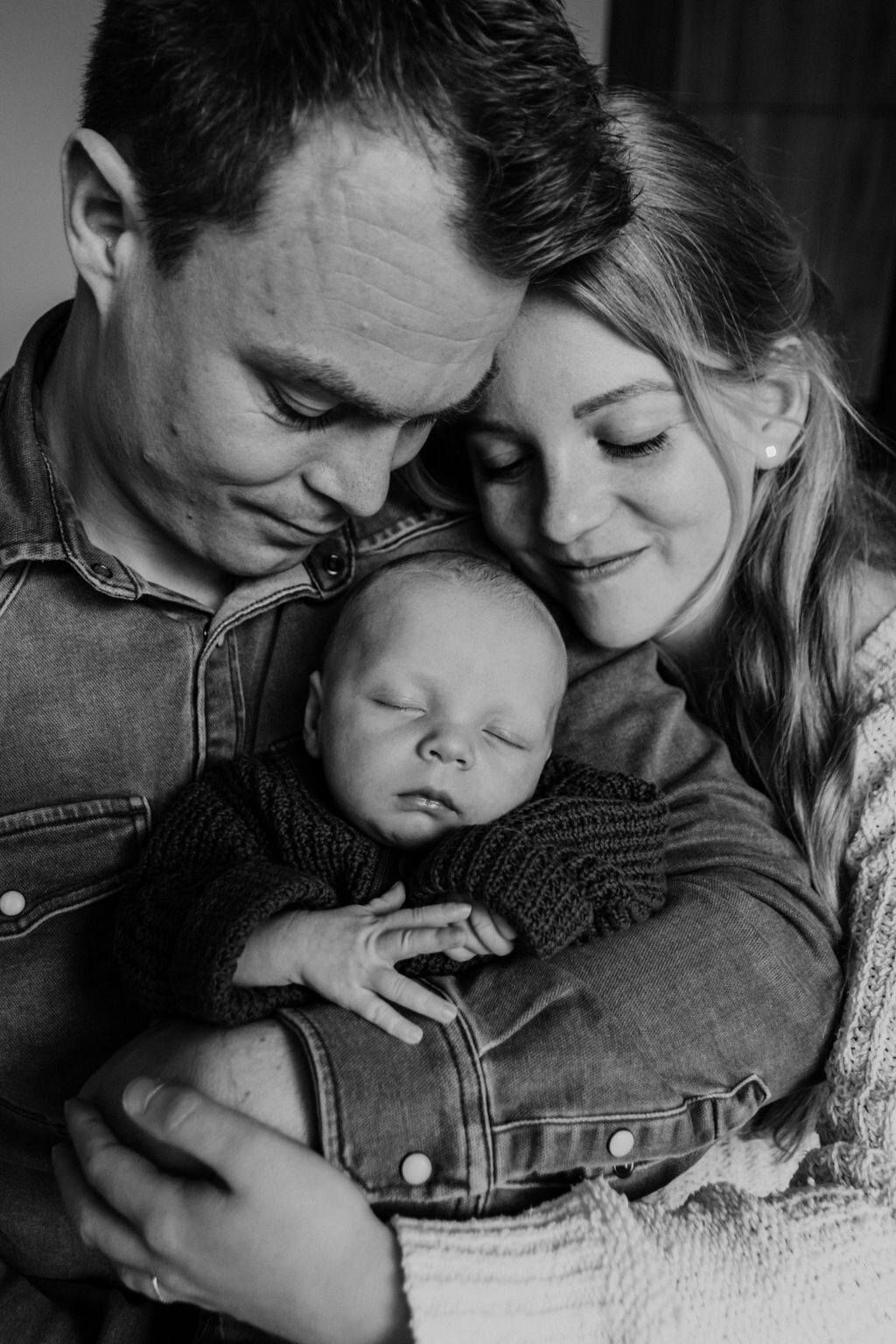 Ouders knuffelen met newborn baby tijdens een newbornshoot in Noord-Nederland