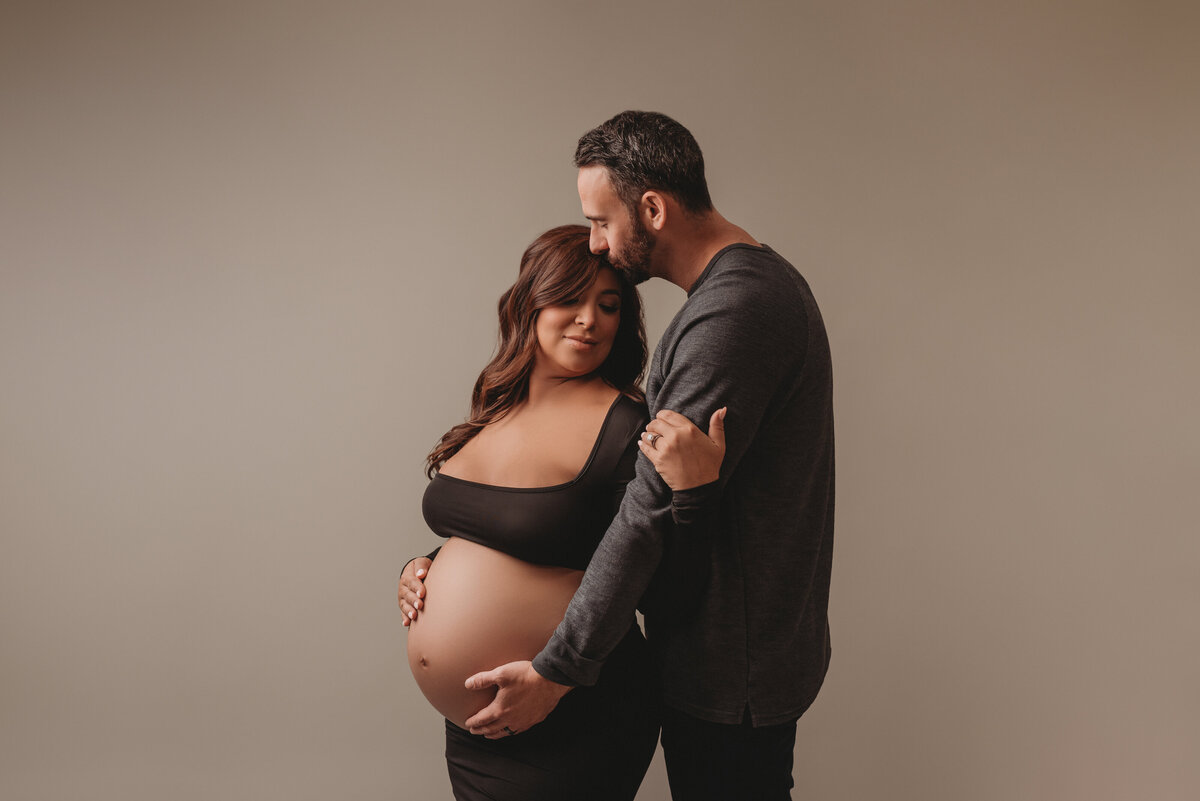 Maternity shoot with Atlanta, Georgia maternity photographer pregnant woman wearing black maternity gown snuggling husband