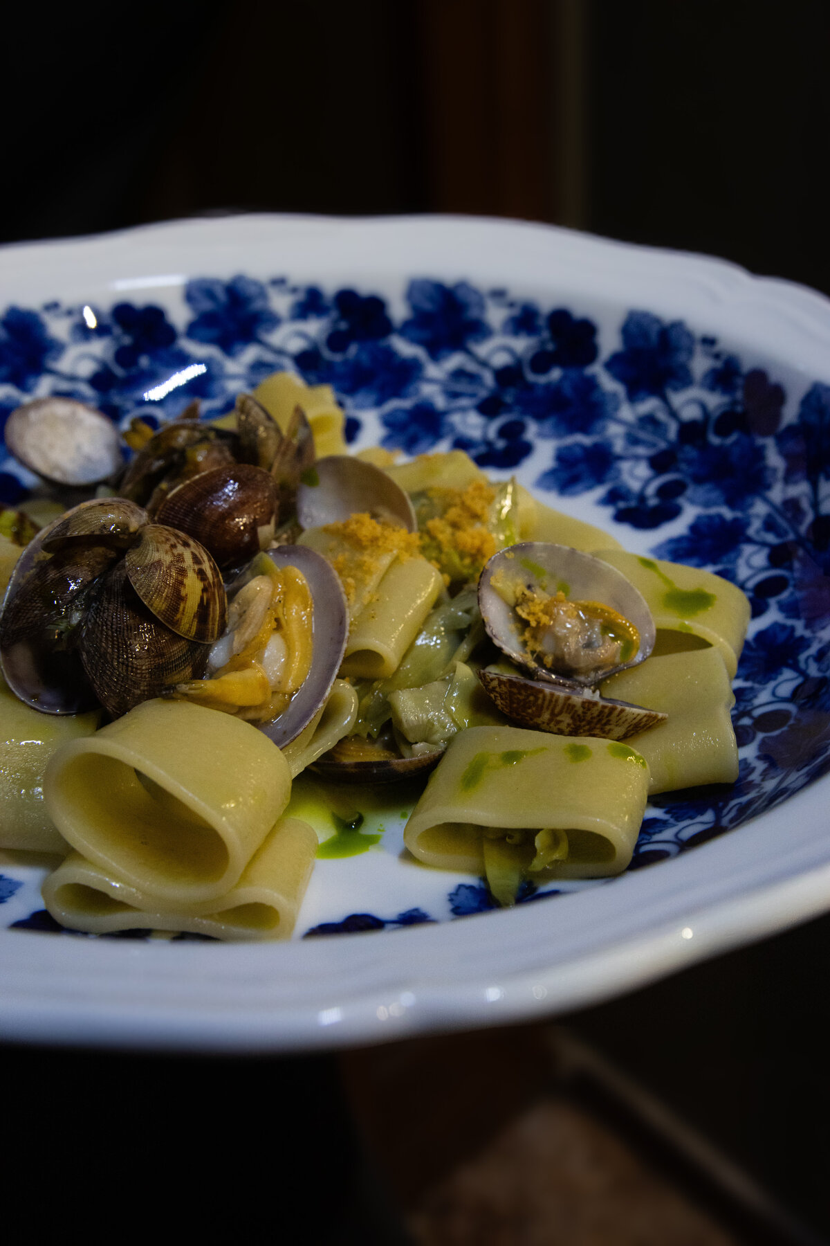 Pasta with clams on blue and white plate.