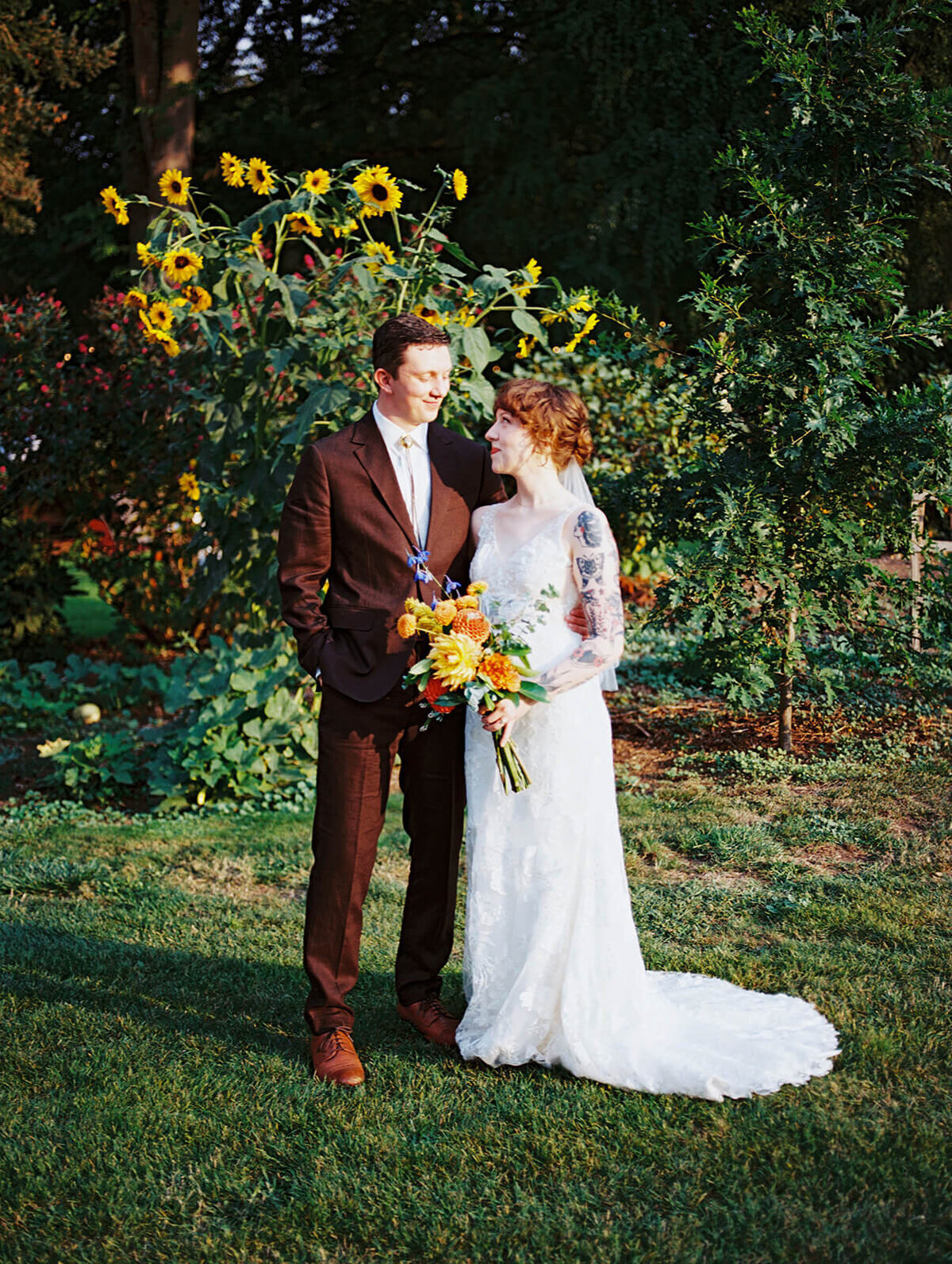 Bride and groom standing happily in front of sunflowers. 