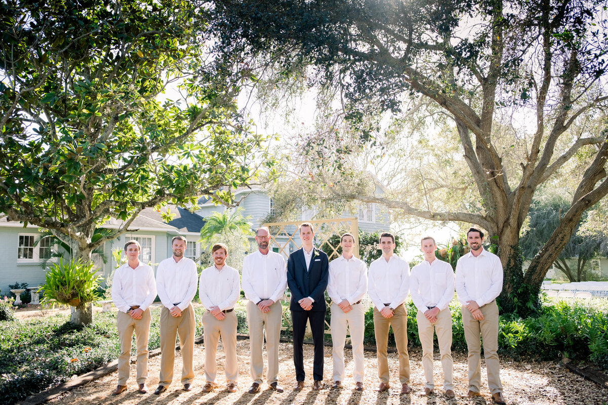 Groom and his groomsmen stand under a canopy of sunlit trees in Palmetto, Florida