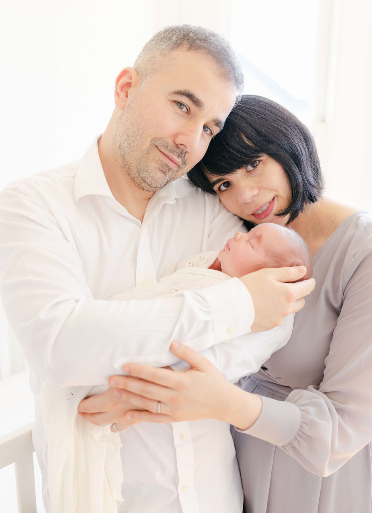 Parents cuddling their newborn during an in-home San Francisco Bay Area newborn photographer session.