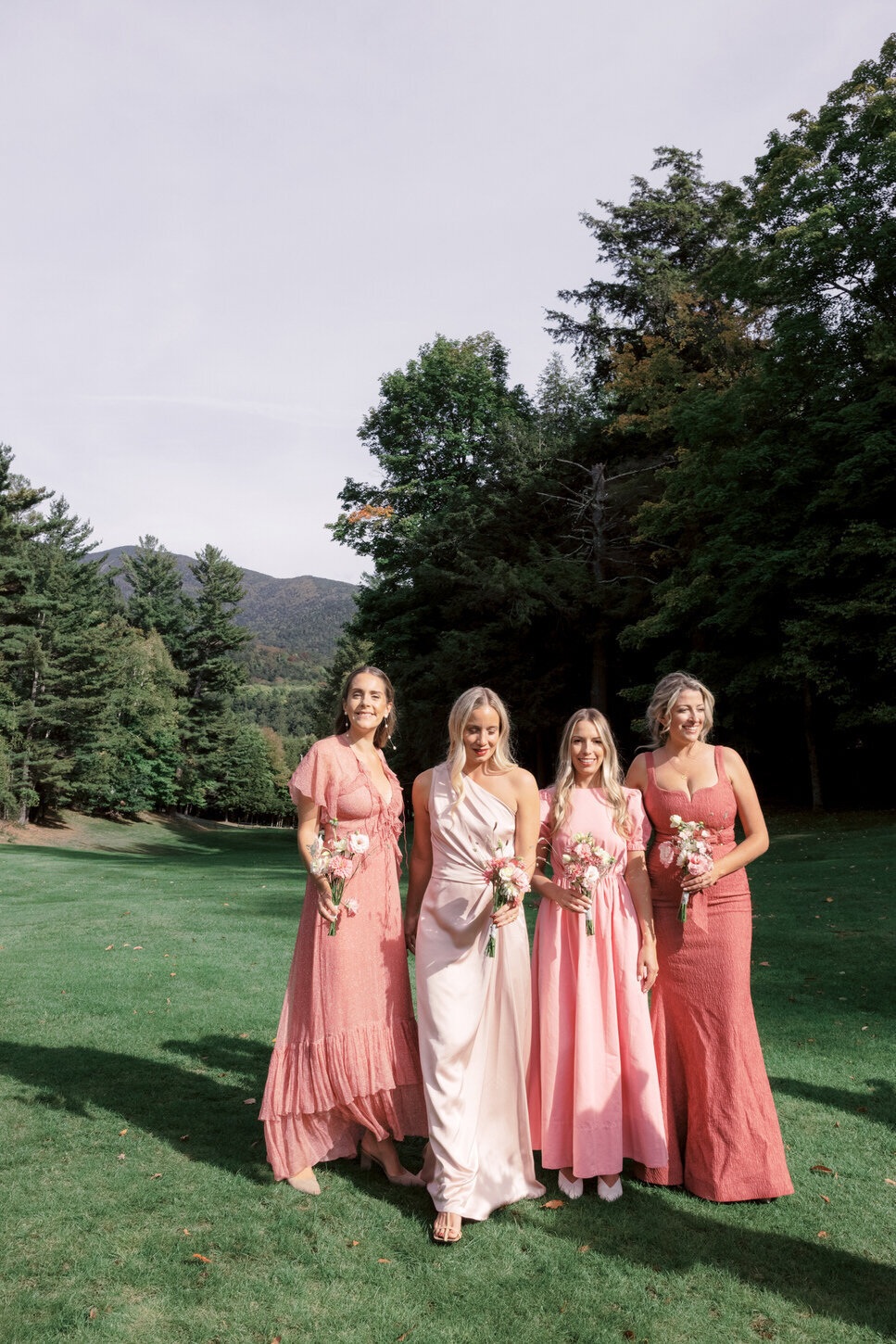 adirondack-mountain-wedding-15-bridesmaids-in-pastel-gowns-gathered-on-the-lawn-with-mountains-in-view-at-adirondack-mountain-wedding-jenny-fu-studio