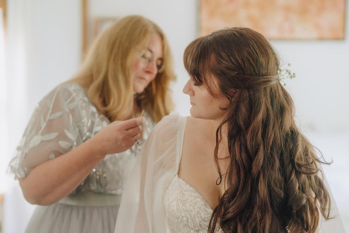 woman helping bride with her dress