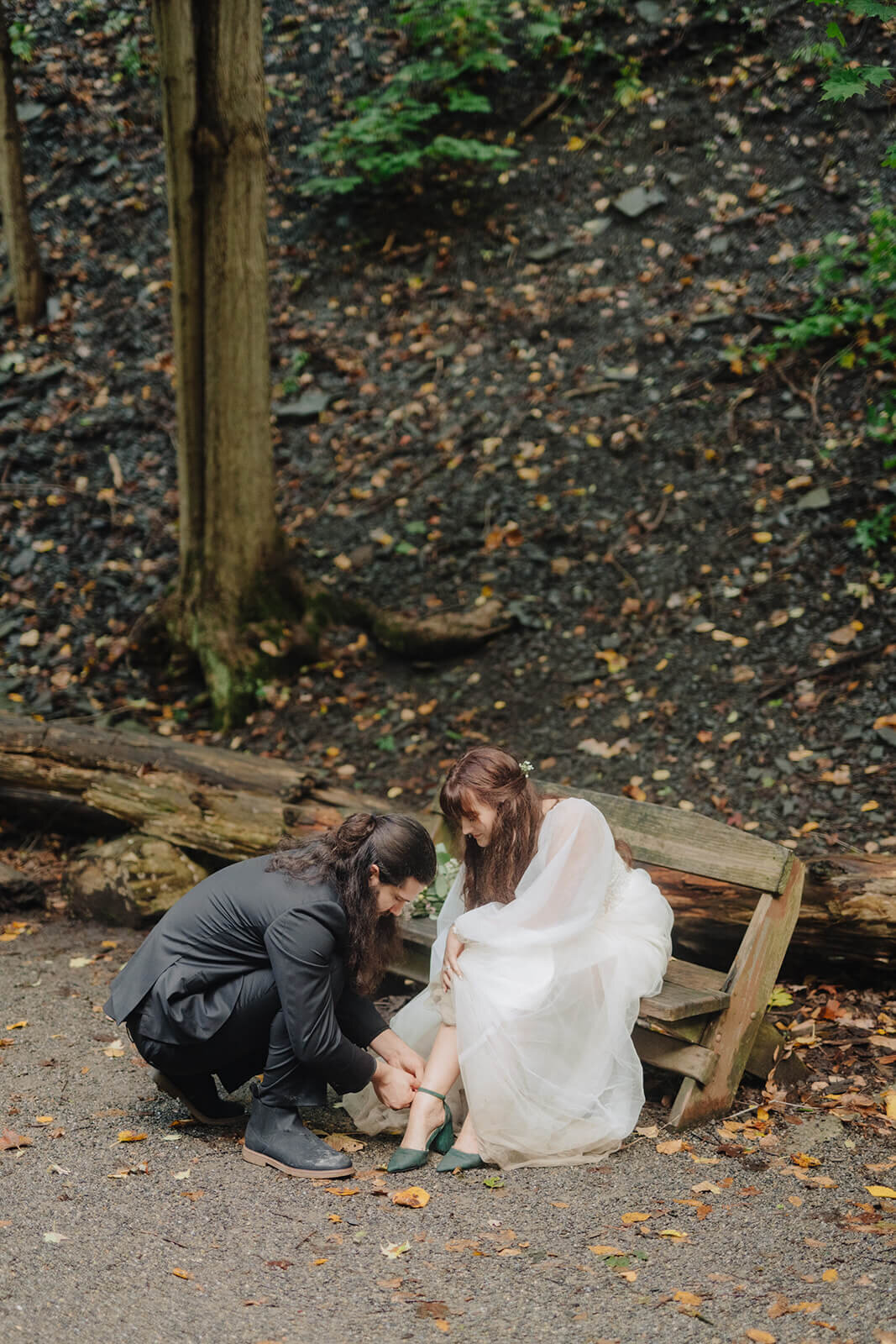 Groom helping bride put on shoes
