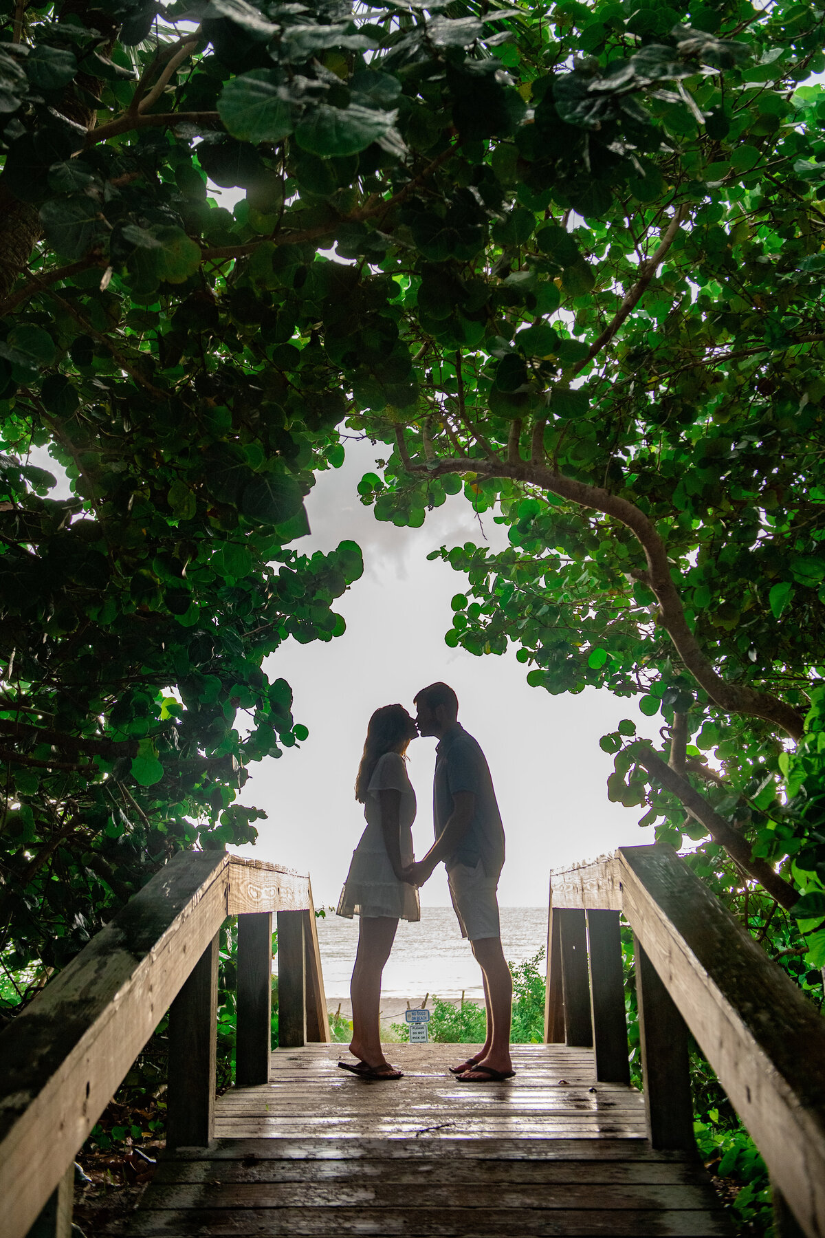secret_kiss_engagement_photo_under_trees_on_bridge