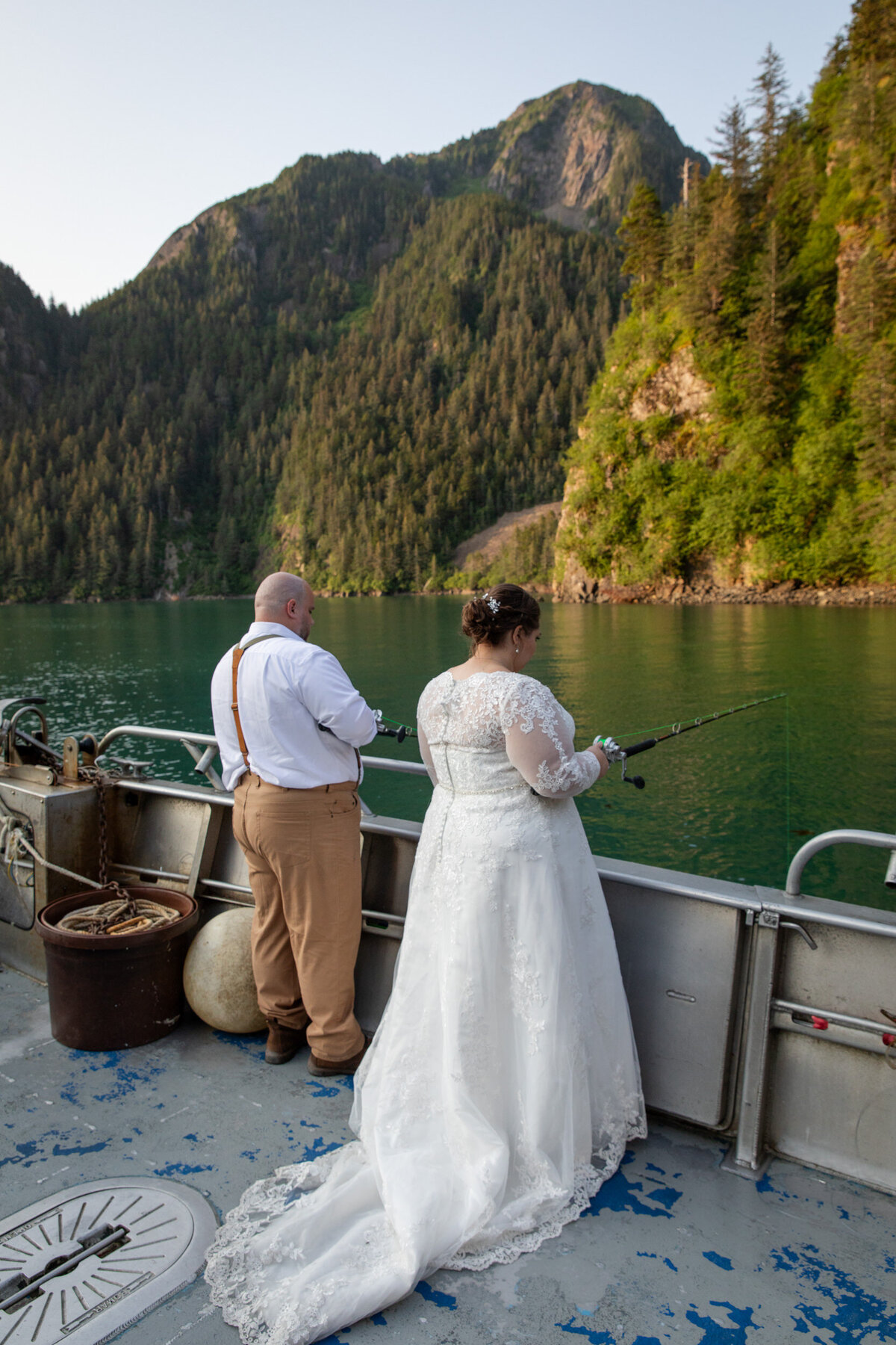 A bride and groom fish off the side of a boat during their elopement in Alaska.