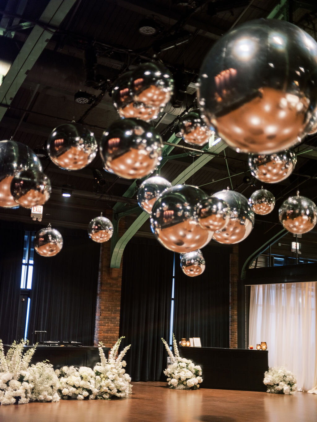 A dramatic wedding reception setup featuring reflective silver spheres hanging from the ceiling, adding a contemporary touch.