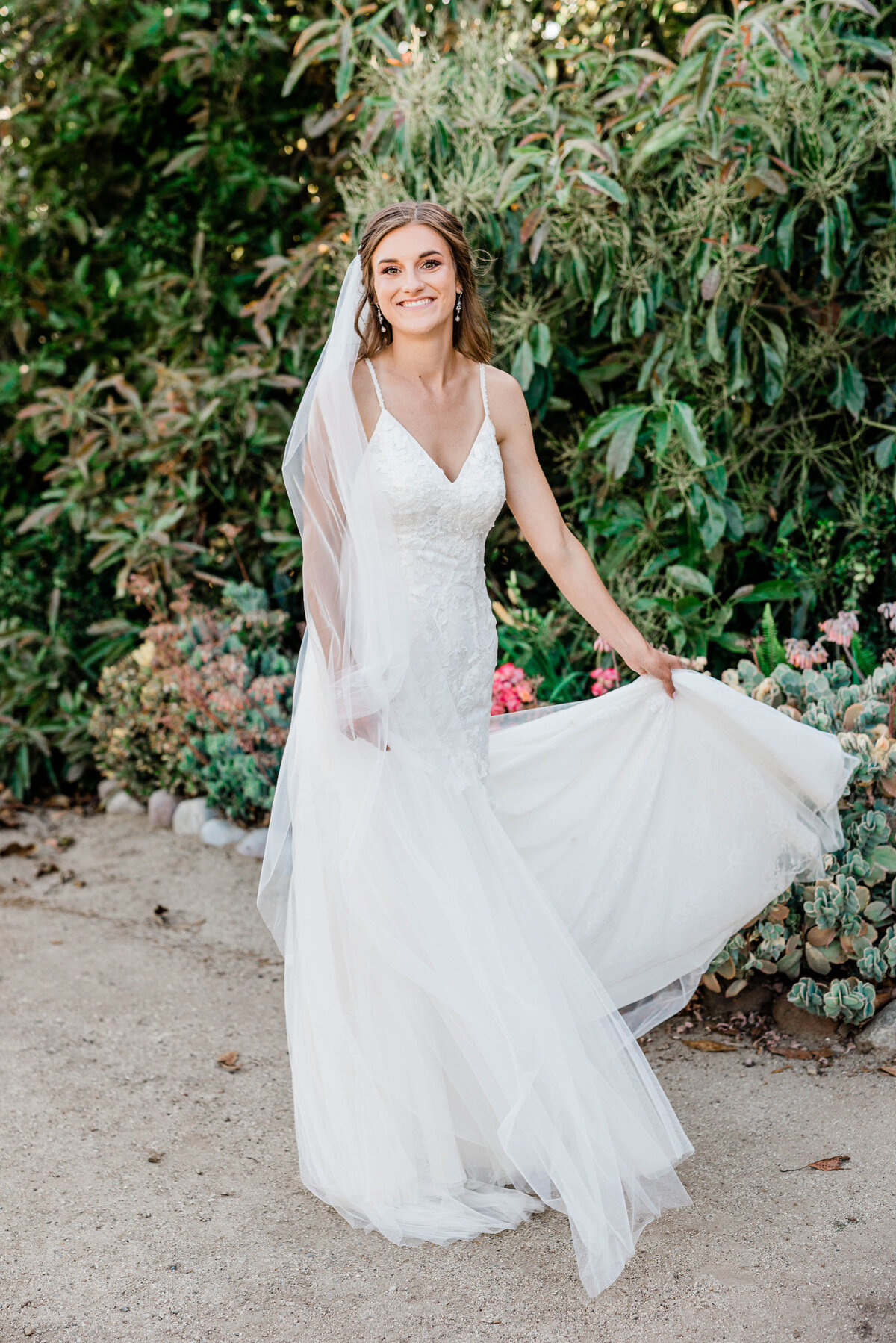 A bride in her wedding dress twirls with joy during her San Luis Obispo wedding day at a vineyard.