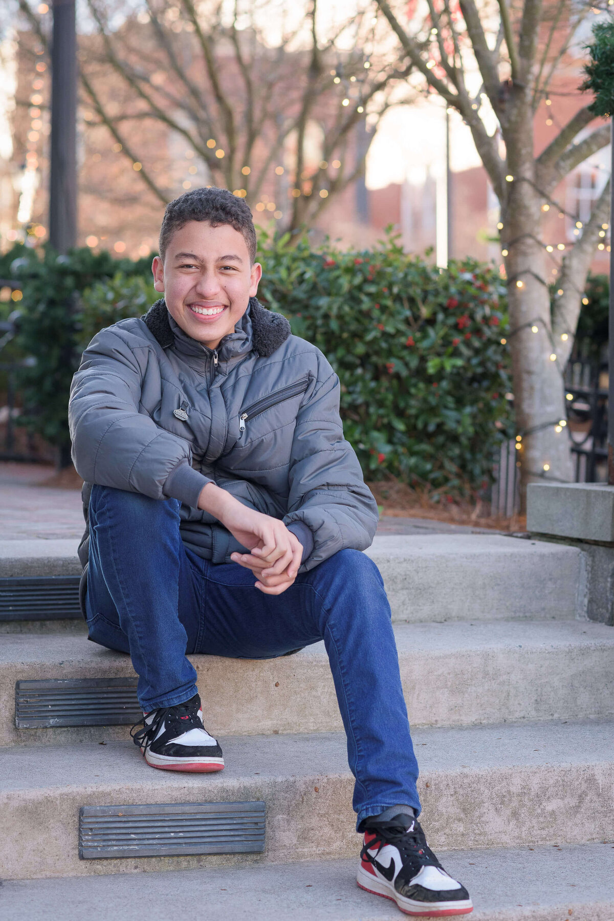 Junior high school boy sitting on a steps resting his elbow on his knee and holding his hands together