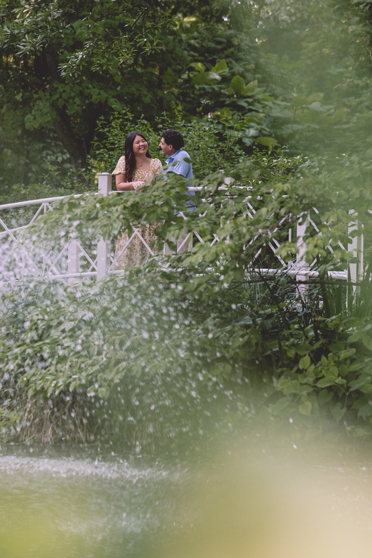 Romantic shot of couple on a garden bridge surrounded by greenery.