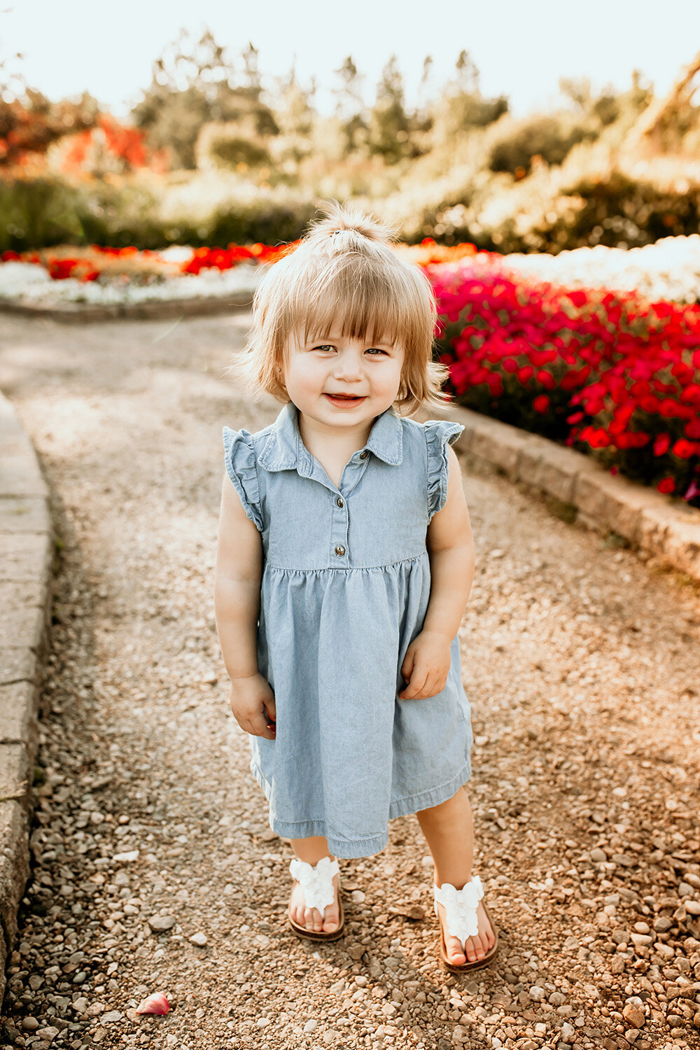 little girl in blue dress standing in garden