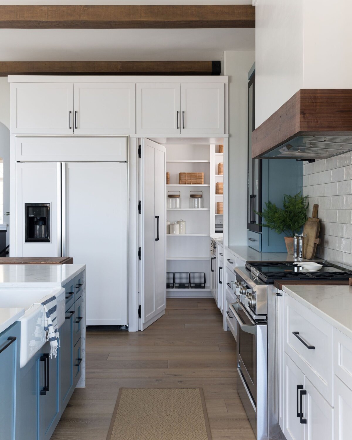 white kitchen with hidden pantry, blue cabinets, and wood accents