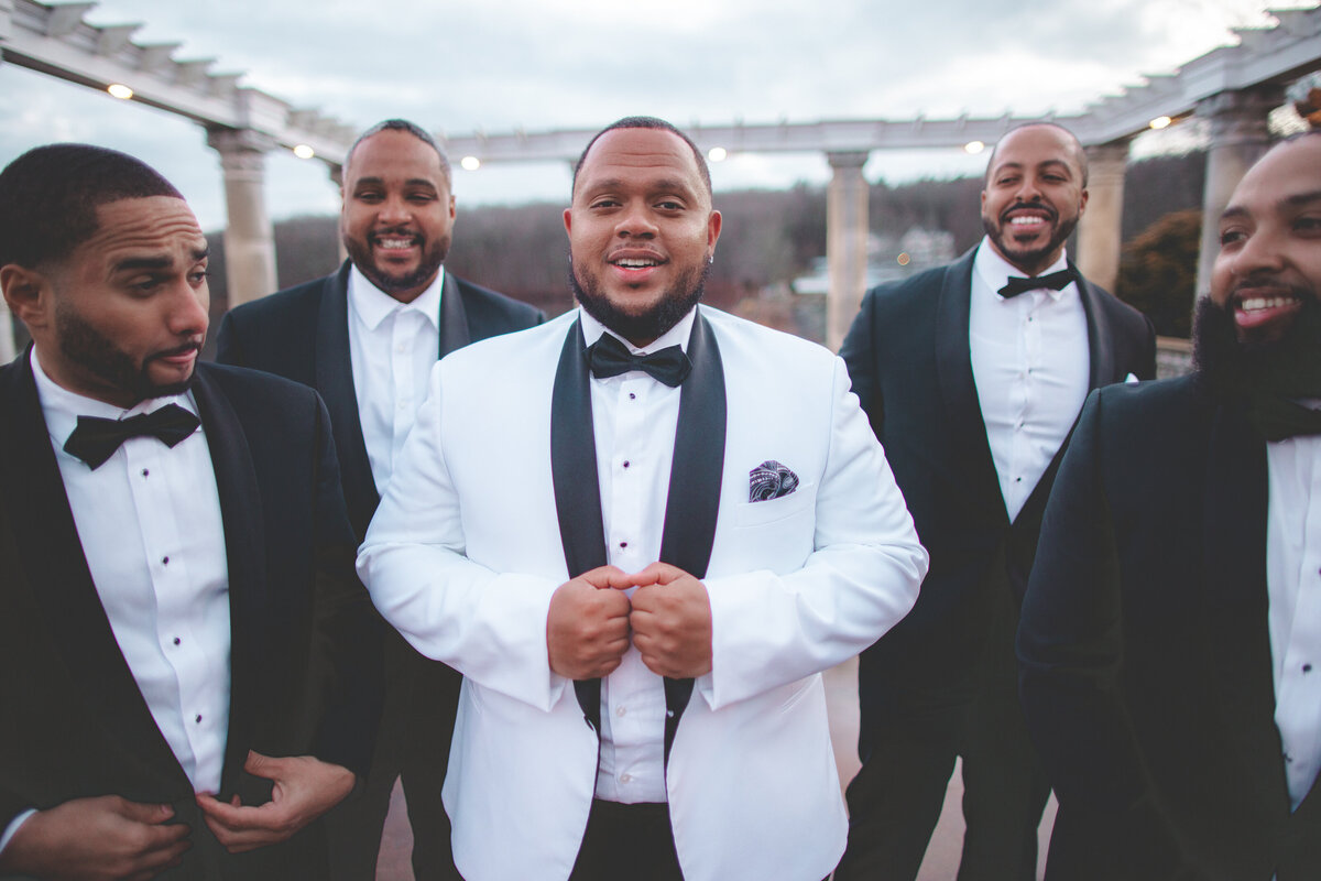Groom surrounded by groomsmen holding their suit jackets