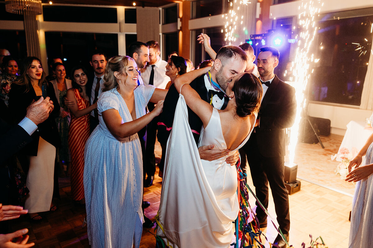Bride and groom kiss and friends cheer after their first dance as newlyweds at The Marion in Canberra ACT