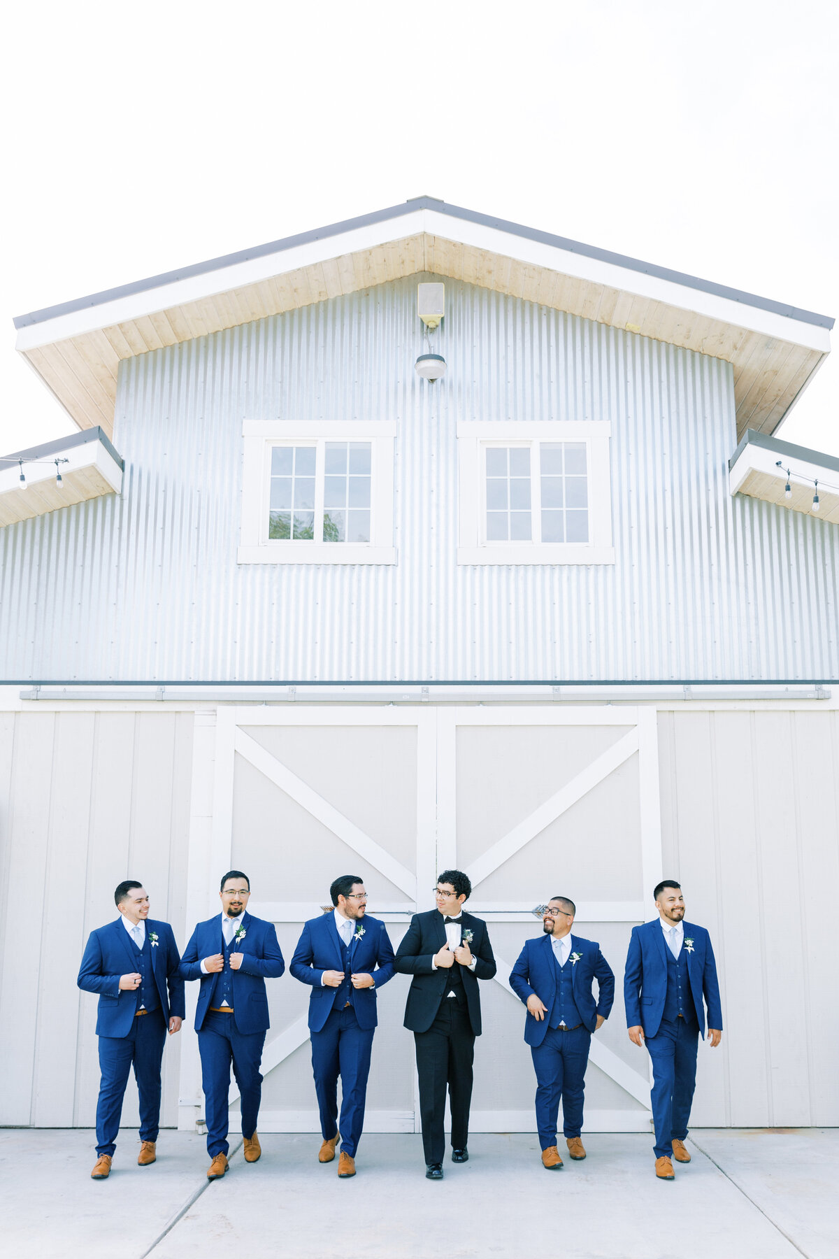 groom and groomsmen in navy suits at barn wedding venue