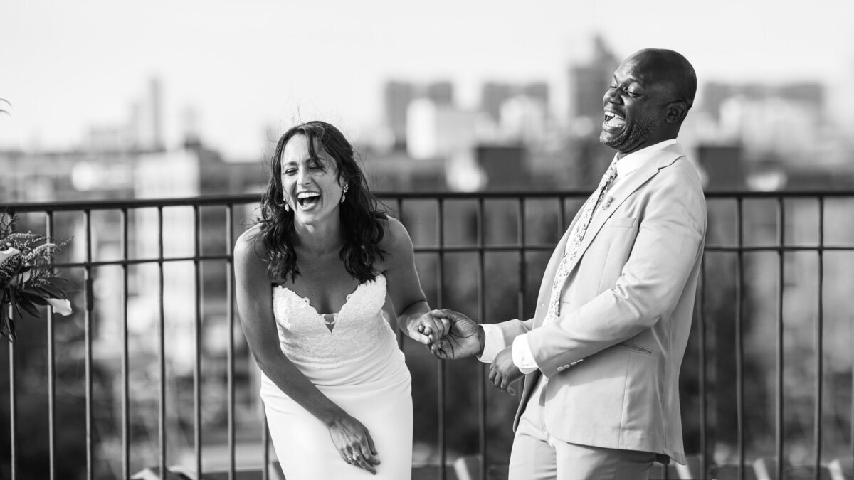 A bride and groom holding hands and laugh on the rooftop of lacuna lofts.
