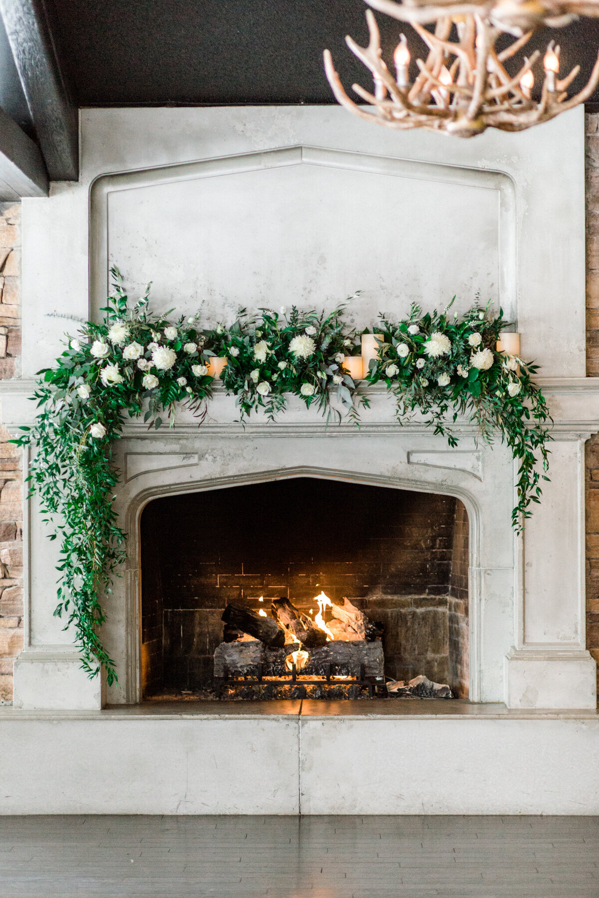 Stunning fireplace mantel with peach and white florals and cascading greenery by Flowers By Janie, artful Calgary, Alberta wedding florist, featured on the Brontë Bride Vendor Guide.