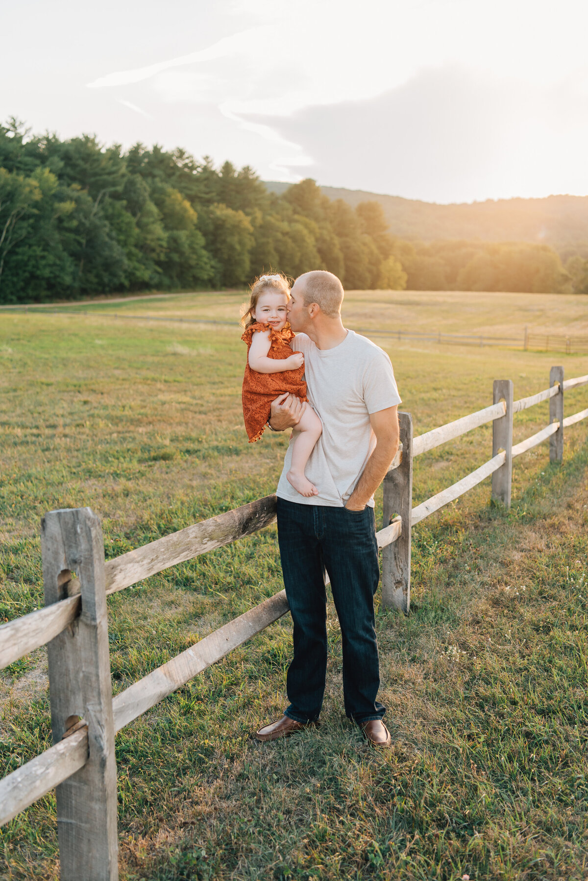 Father kissing young daughter in field