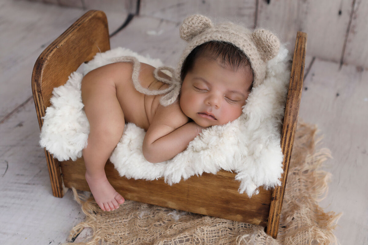 Little-baby-boy-posed-in-a-little-wooden-bed-for-his-newborn-shoot