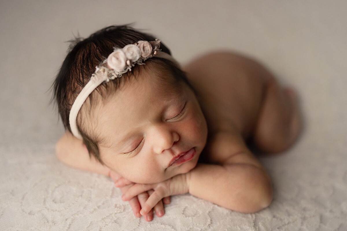 Baby girl laying on her hands in her photo shoot