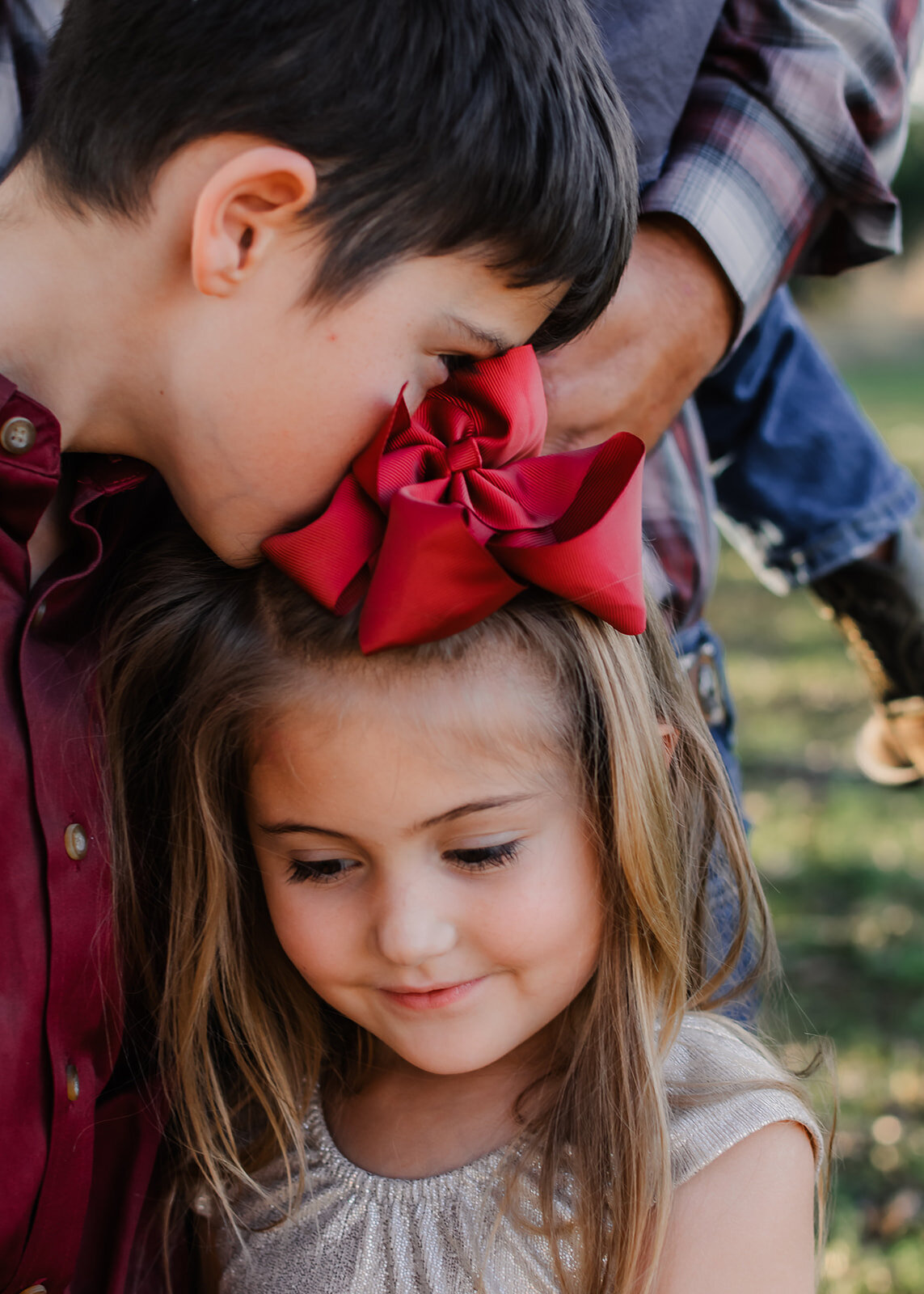 Brother kissing his sisters head, and sister has a sweet smile.