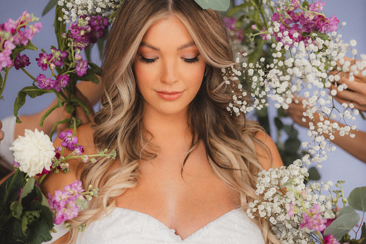 A woman looks down surrounded by flowers