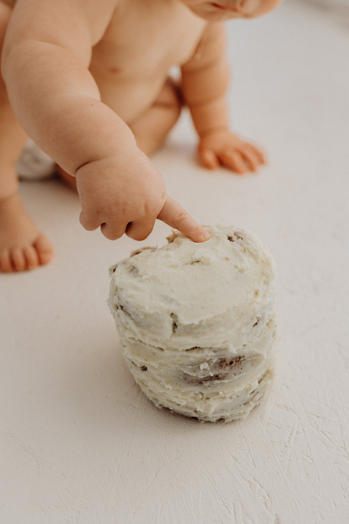 A close up macro shot of a baby touching his milestone cake during a photoshoot