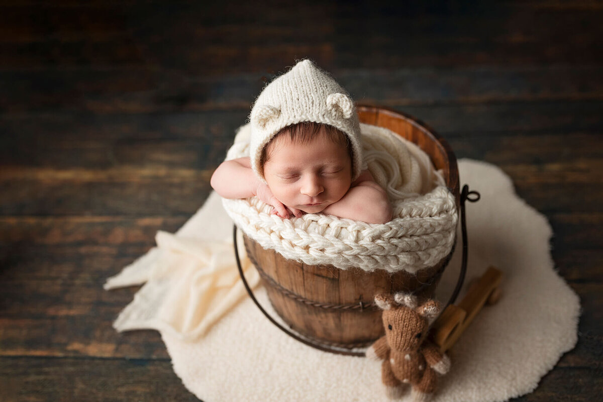 Little boy in an old water bucket during his newborn photo session in Minnesota.