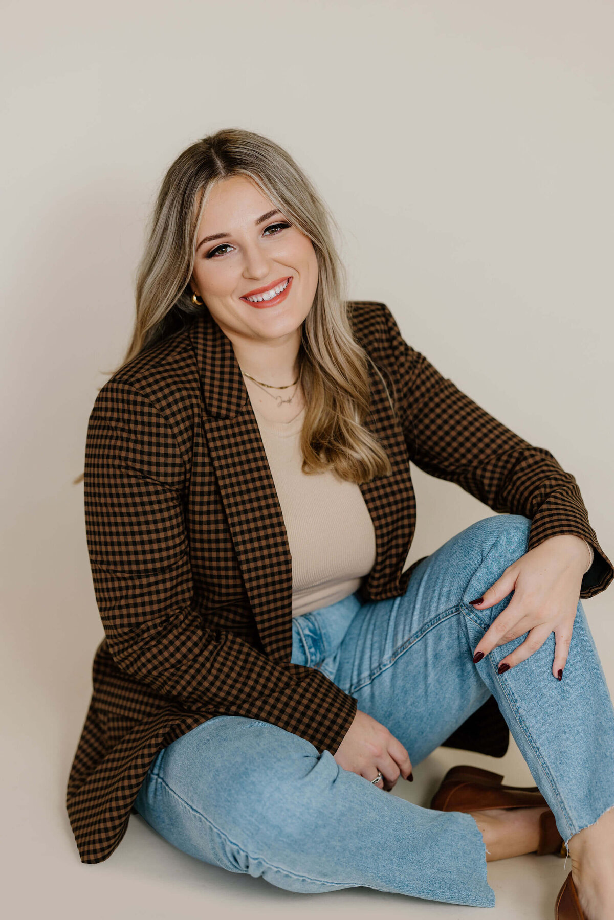 studio portrait of University of TX graduate student in jeans, tan top, and brown blazer